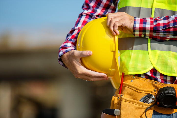 Young construction worker holding a yellow helmet